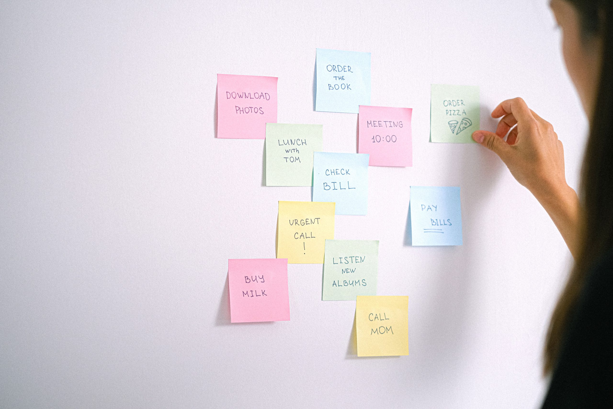 Adult organizing daily tasks and reminders with colorful sticky notes